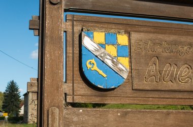 Nahaufnahme des Holzschildes mit Aufschrift Erholungsort Auen und Wappen der Ortsgemeinde.