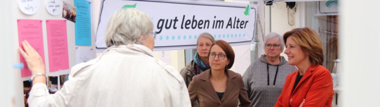 Foto einer Veranstaltung von vier Personen, darunter die Ministerpräsidentin von Rheinland-Pfalz Malu Dreyer, vor einer Metaplanwand und einem Banner der Initiative "So-gut-leben-im-Alter".